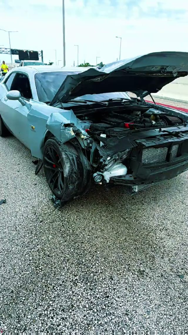 Dodge Challenger with a crushed front end on the highway
