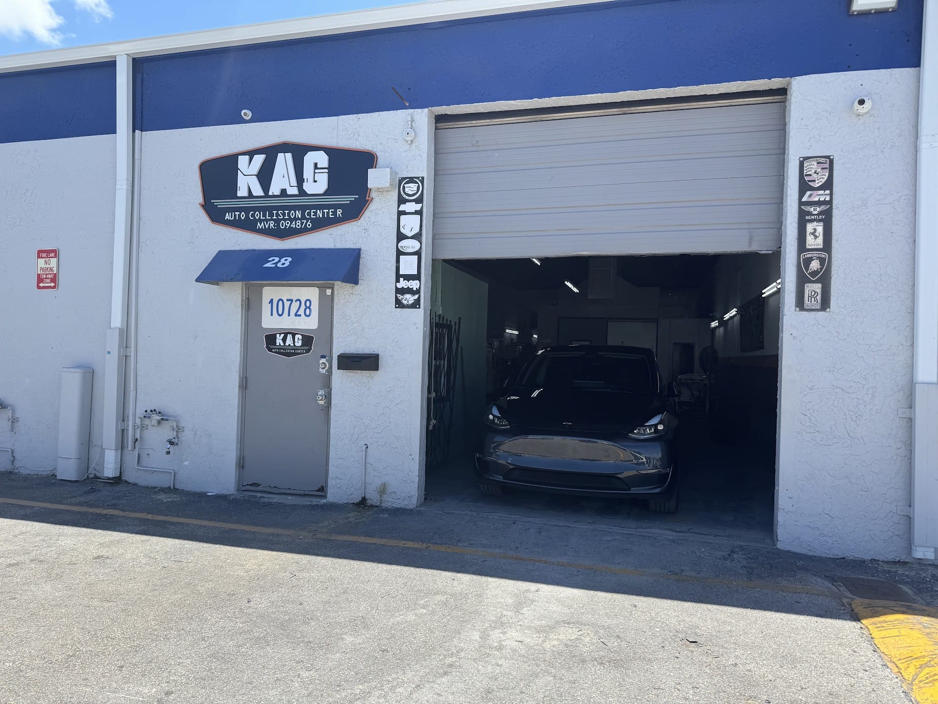 KAG Auto Collision Center storefront, Bay 28, with a Tesla Model Y inside